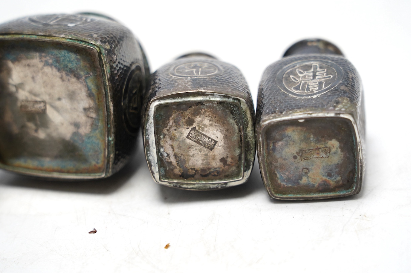 A Chinese embossed white metal cylindrical jar and cover, 11.2cm, and a similar white metal four piece cruet set. Condition - poor to fair